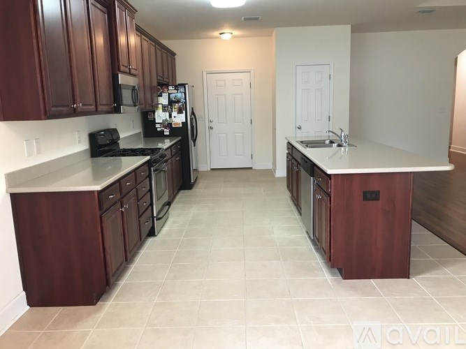A kitchen with dark wood cabinets and white countertops.