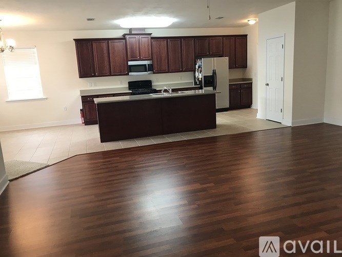 A kitchen with dark wood cabinets and a dark brown island.