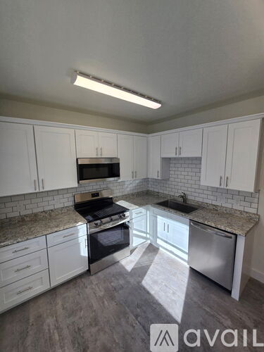 A kitchen with white cabinets and a black stove top oven.