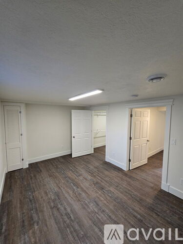 A room with wooden flooring and white walls.