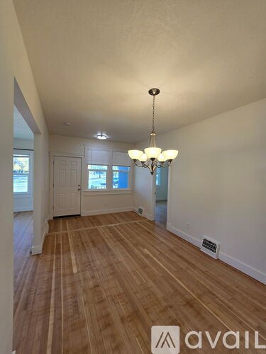 A room with wooden floors and a chandelier hanging from the ceiling.
