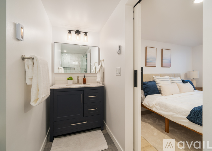 A bathroom with a sink, mirror, and a towel hanging on the wall.