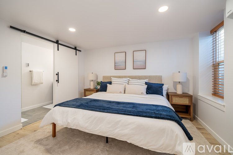 A bedroom with a bed, nightstand, and sliding door.