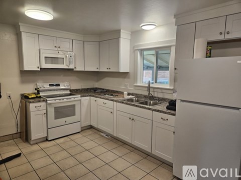 A kitchen with white cabinets and appliances.