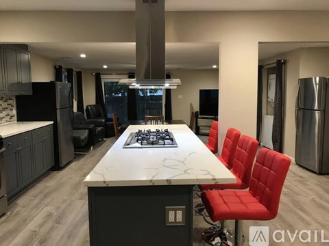 A modern kitchen with a large island and red chairs.