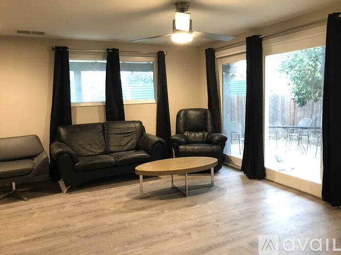 A living room with black leather furniture and a wooden coffee table.