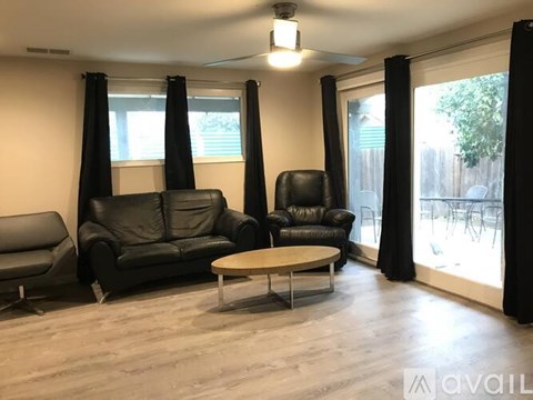 A living room with black leather furniture and a wooden coffee table.