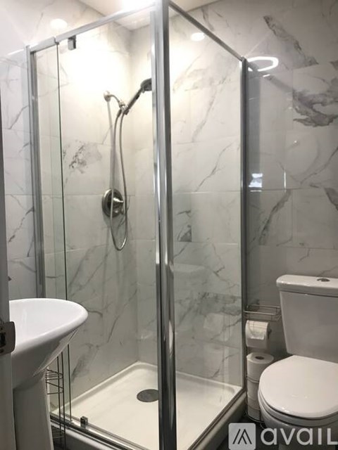 A bathroom with a marble wall and a glass shower stall.