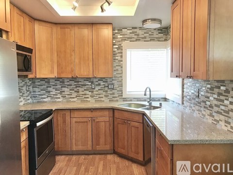 A kitchen with wooden cabinets and a black refrigerator.