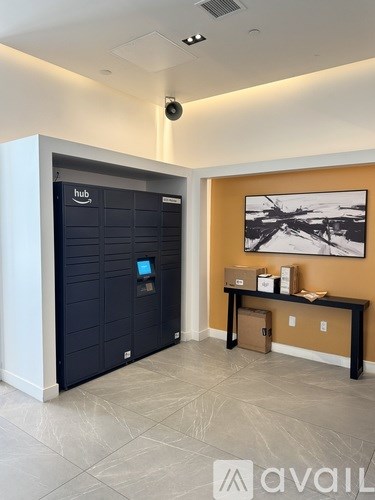A black Amazon Locker unit sits in a room with a brown wall and a black bench.