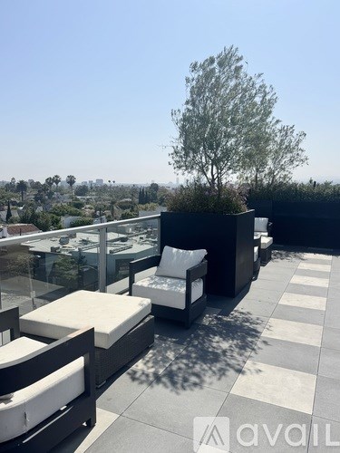 A patio with white cushions and a tree in the background.