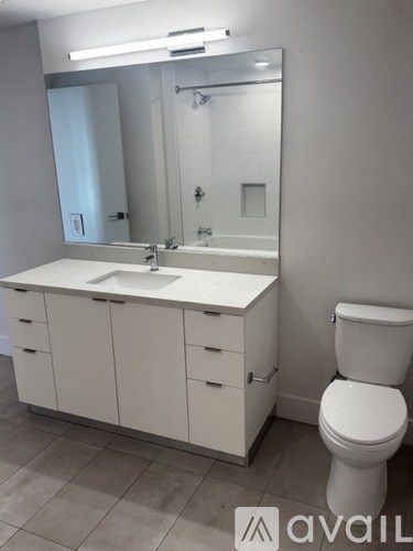 A white bathroom with a toilet, sink, and mirror.