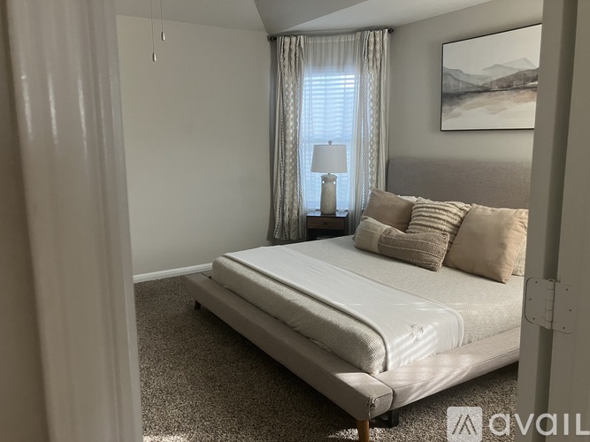 A bedroom with a large bed and a painting on the wall.