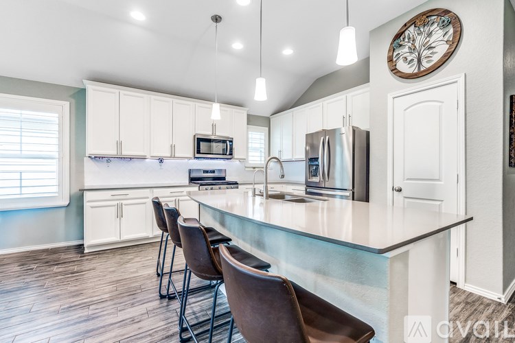 A kitchen with a white island and brown chairs.