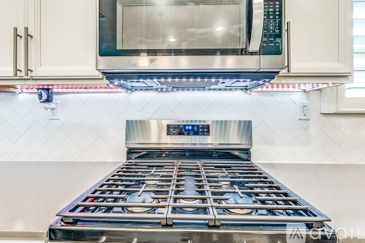 A modern kitchen with a stainless steel stove top and microwave above it.