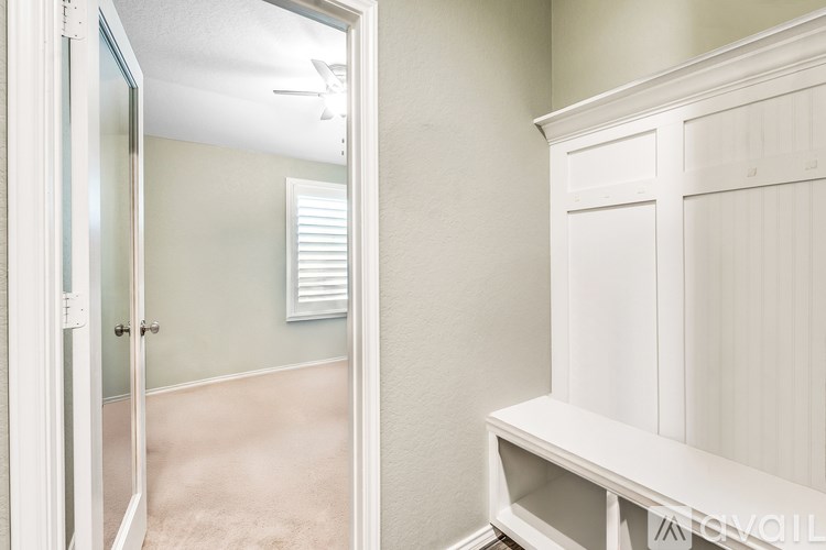 A white bench is in a room with a white door and a white cabinet.
