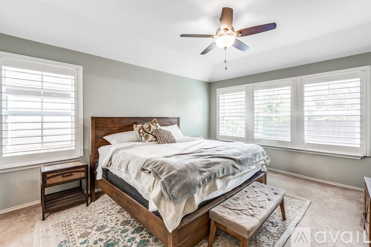 A bedroom with a bed, a ceiling fan, and a window with blinds.