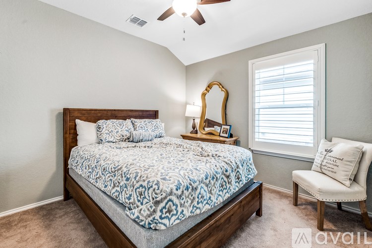 A bedroom with a bed, chair, and a mirror.