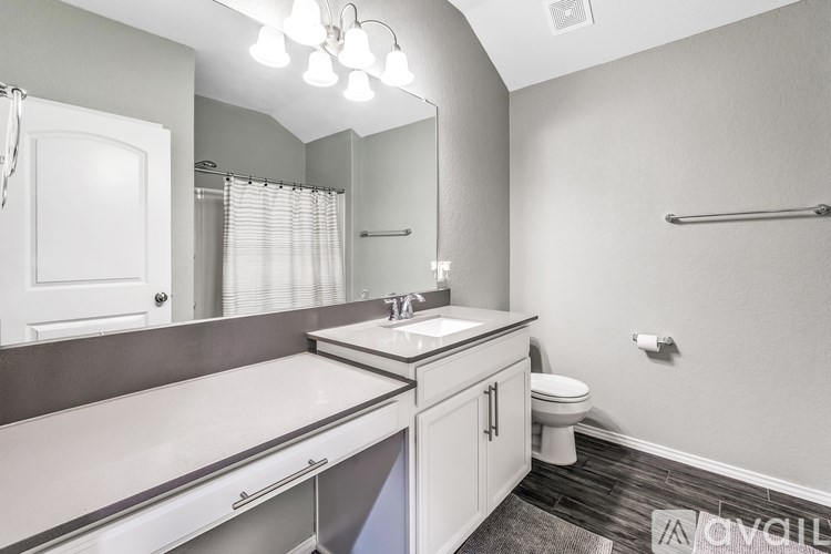 A bathroom with a toilet, sink, and mirror.
