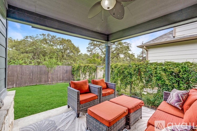 A patio with orange cushions and a ceiling fan.