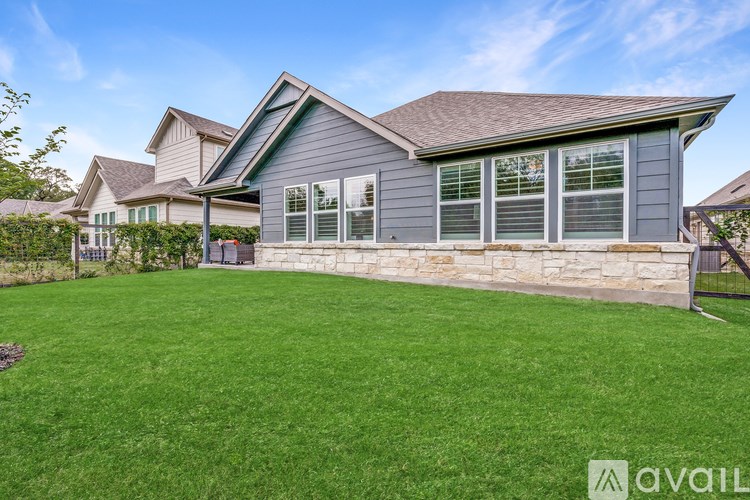 A house with a stone wall and a green lawn is available for sale.