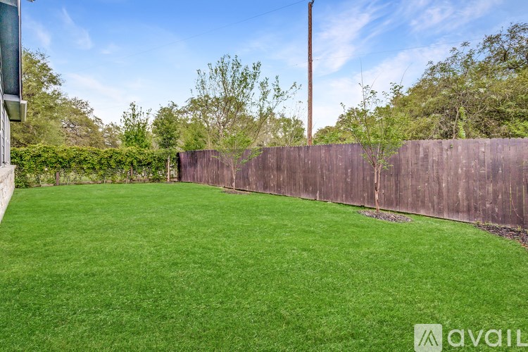 A backyard with a wooden fence and a green lawn.