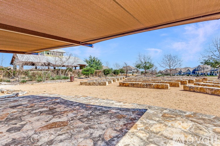 A large open area with a stone floor and a shade structure overhead.