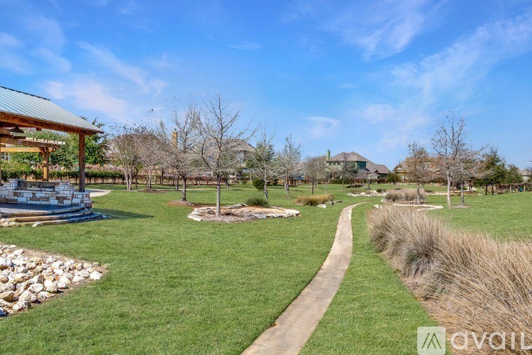 A grassy area with a walking path and a building in the background.