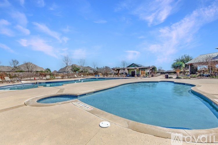 A large outdoor swimming pool with a blue sky and some clouds in the background.