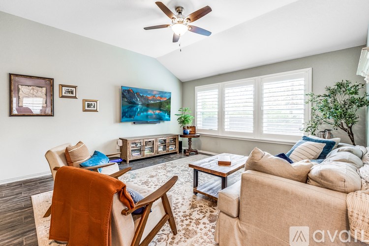 A living room with a beige couch, a wooden chair, and a ceiling fan.