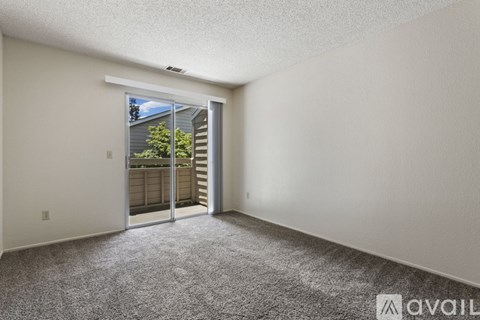 A room with a carpeted floor and a sliding glass door leading to a balcony.
