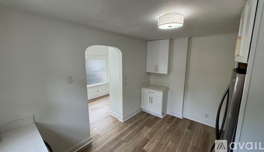 A kitchen area with white cabinets and a wooden floor.