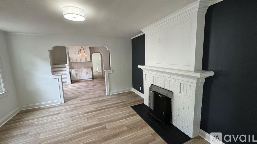 A white fireplace in a room with wooden flooring and white walls.