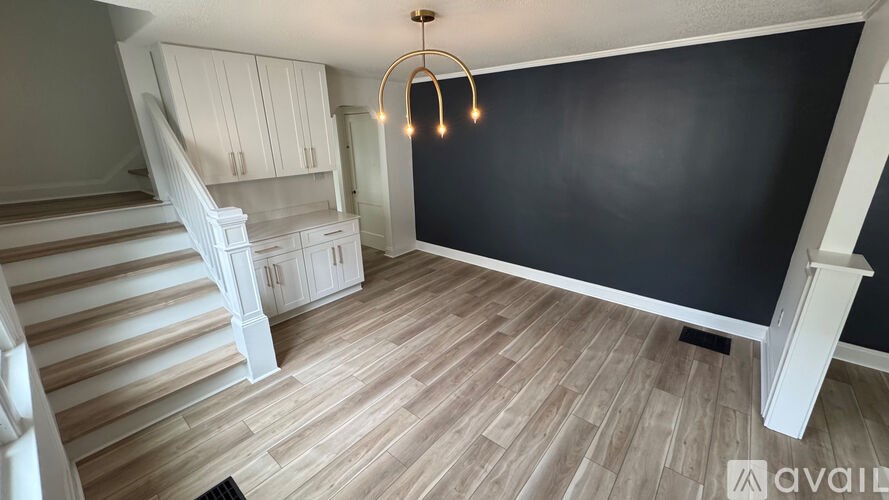 A room with wooden flooring and a staircase with white railings.