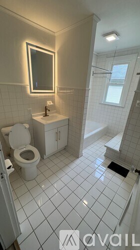 A bathroom with a toilet, sink, and mirror.