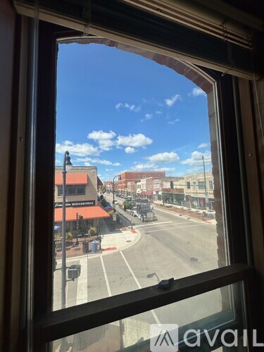 A view from a window looking out at a street with buildings and a clear sky.