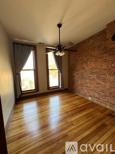 A room with wooden floors and a brick wall.