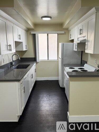 A kitchen with white cabinets and black countertops.