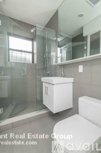 A white toilet sits next to a walk-in shower in a modern bathroom.