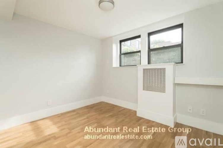A room with wooden flooring and two windows.