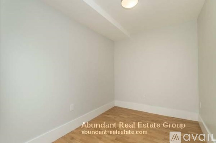 A room with a wooden floor and white walls is available for rent.