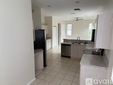 A kitchen with white cabinets and a black fridge.