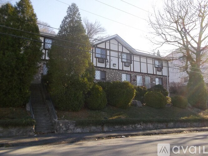 A house with a black and white facade is surrounded by greenery.
