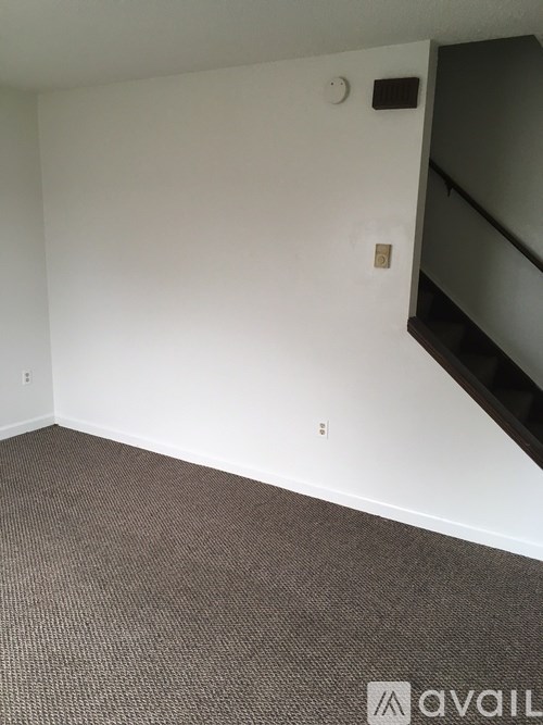 A room with a carpeted floor and a staircase.