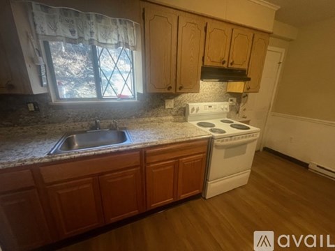 A kitchen with wooden cabinets and a white stove top oven.