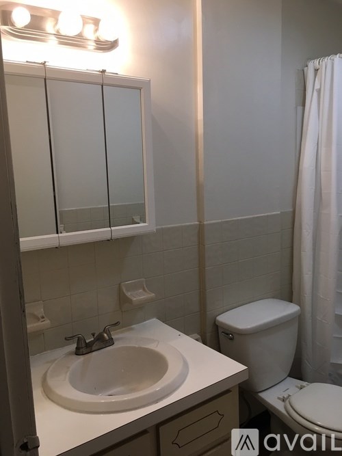 A bathroom with a toilet, sink, and mirror.