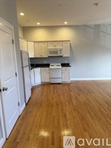 A kitchen with white cabinets and a wooden floor.