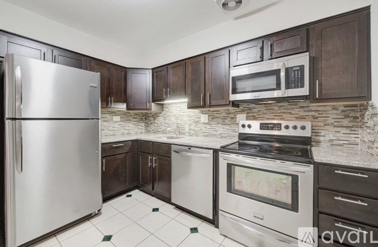 A kitchen with a stainless steel refrigerator, microwave, oven, and black cabinets.