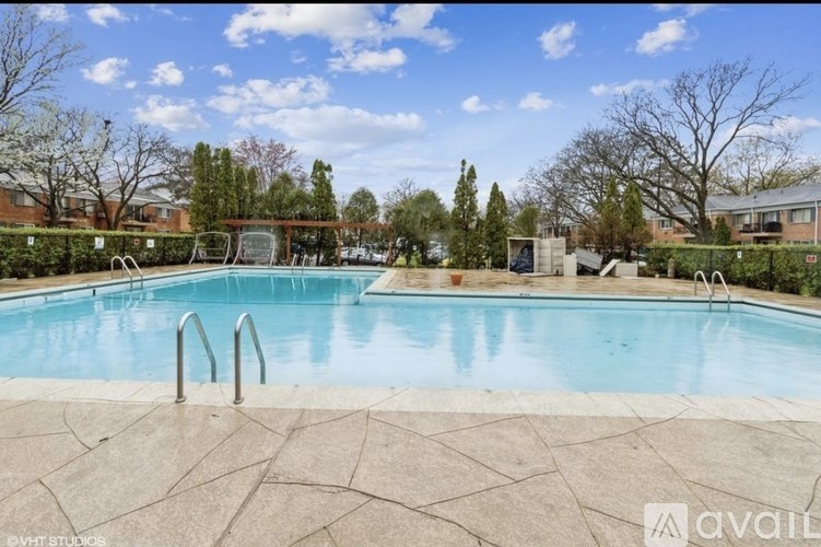 A swimming pool surrounded by a stone patio and trees.