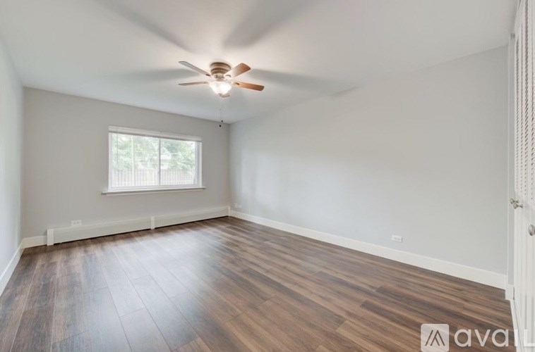 A room with wooden flooring and a ceiling fan.